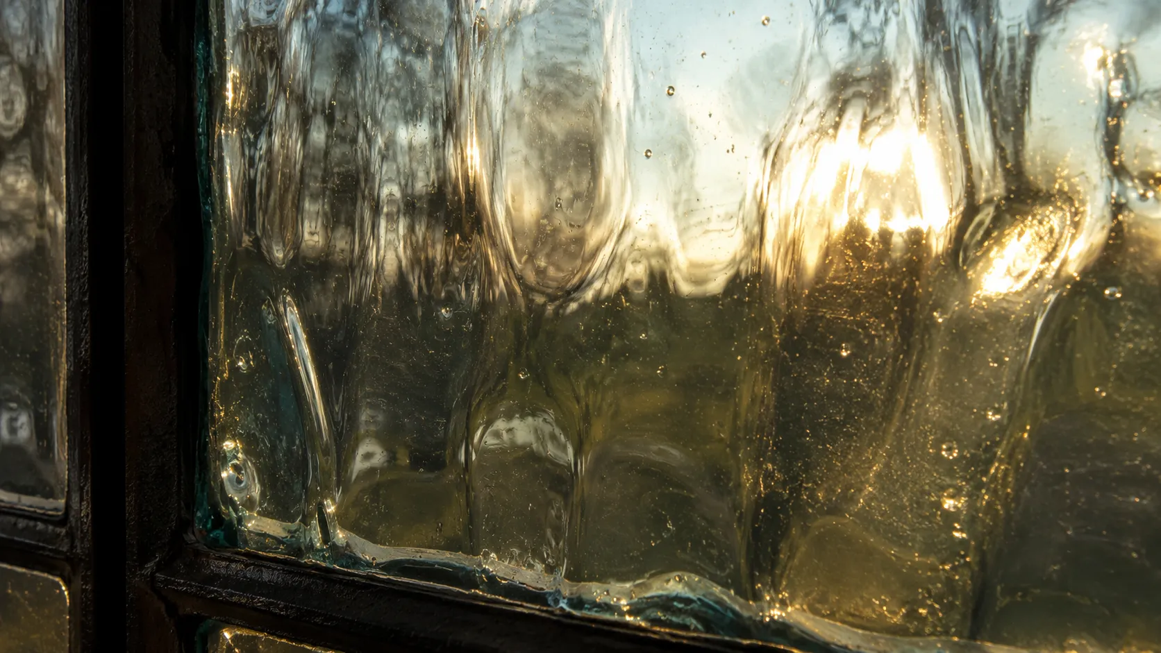 Close-up of an old wavy glass window pane with uneven thickness