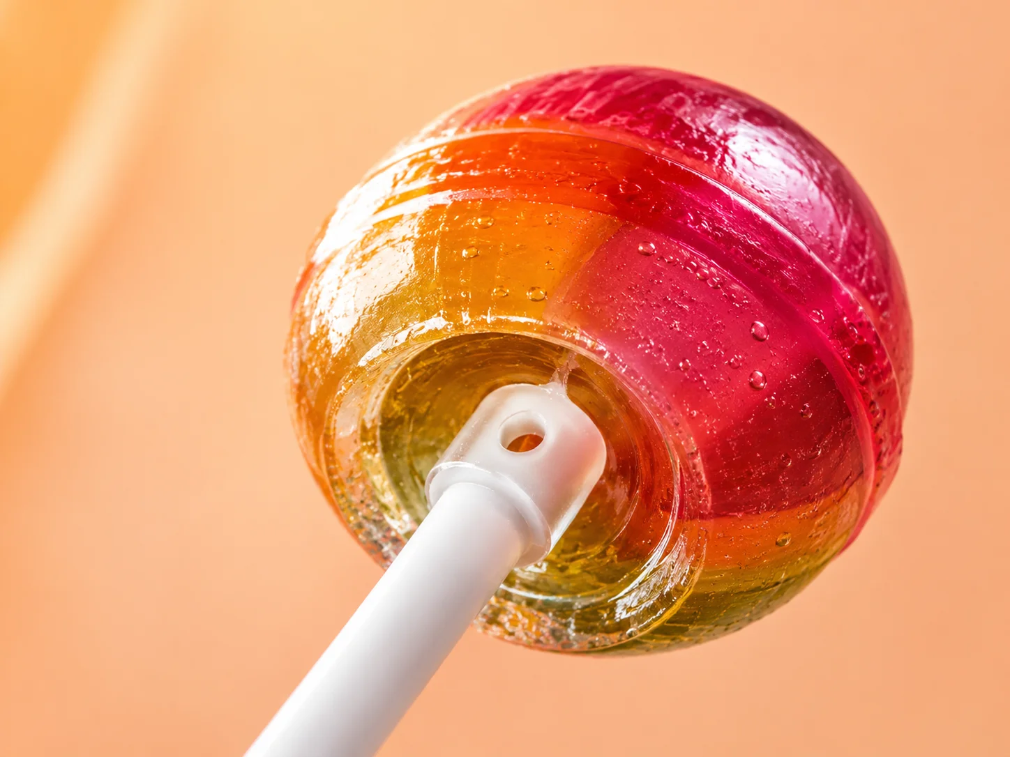 Close-up of a lollipop stick near the candy end, showing the hole that anchors the candy