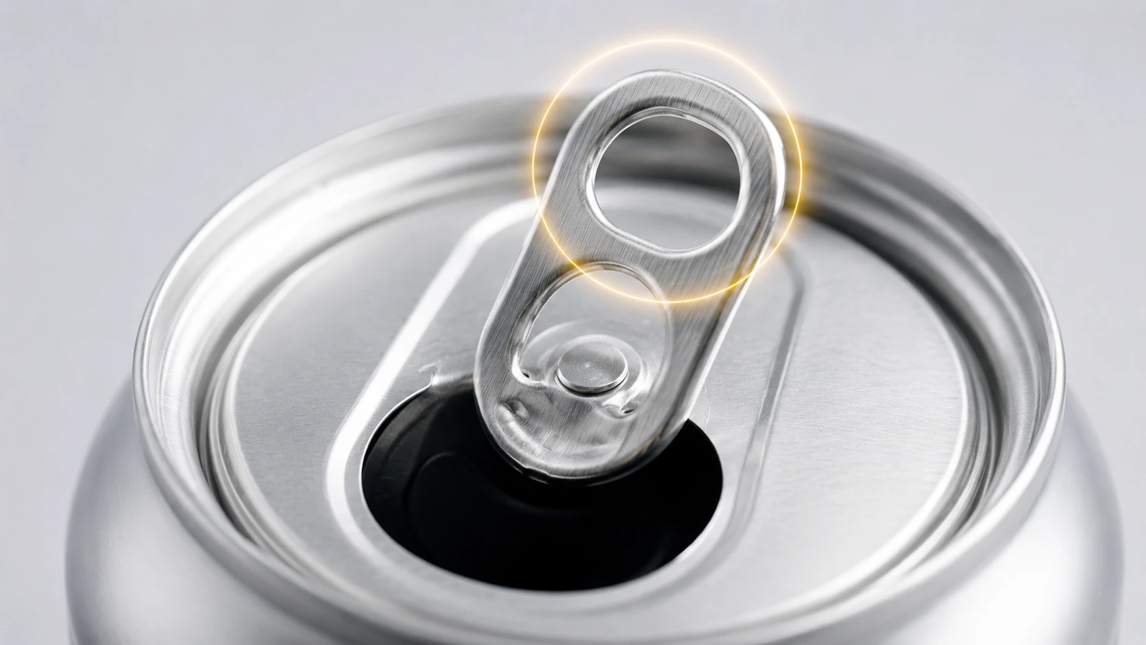 Close-up of a soda can tab showing the finger hole and rivet